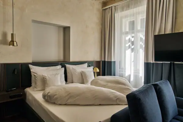 Ein Bett mit Kissen und einer Lampe in einem Zimmer.
