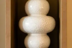 Weiße Vase in einem Holzregal.
