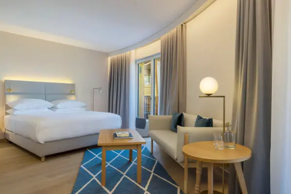 Ein Hotelzimmer im A-ROSA Tegernsee mit einem Bett, einem Sofa und einem kleinen Tisch.