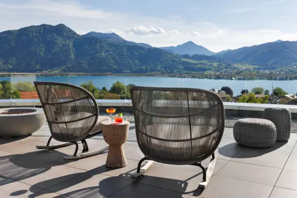 Ein Stuhl und Tisch auf der NI BAR Rooftop-Terrasseck auf einen See.
