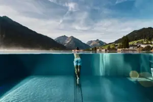 Ein Mann in einem Pool mit Bergen im Hintergrund.