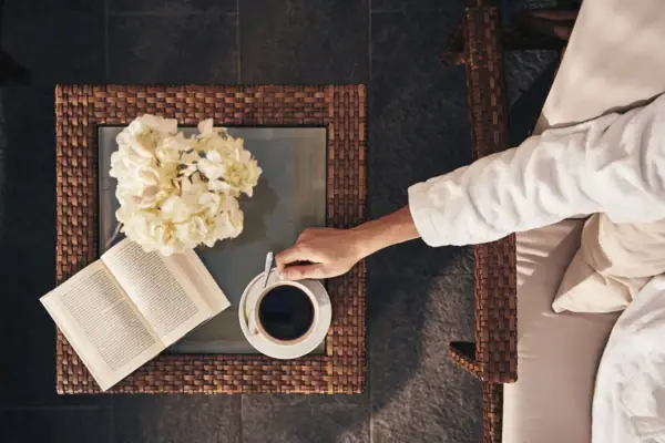 Eine Person hält eine Tasse Kaffee und ein Buch.