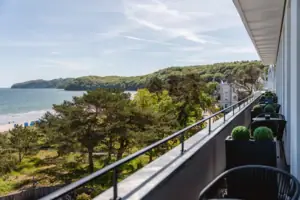 Balkon mit Blick auf einen See unter wolkenbedecktem Himmel.