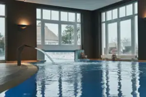 Ein Innenpool mit Wasserfall und großen Fenstern.