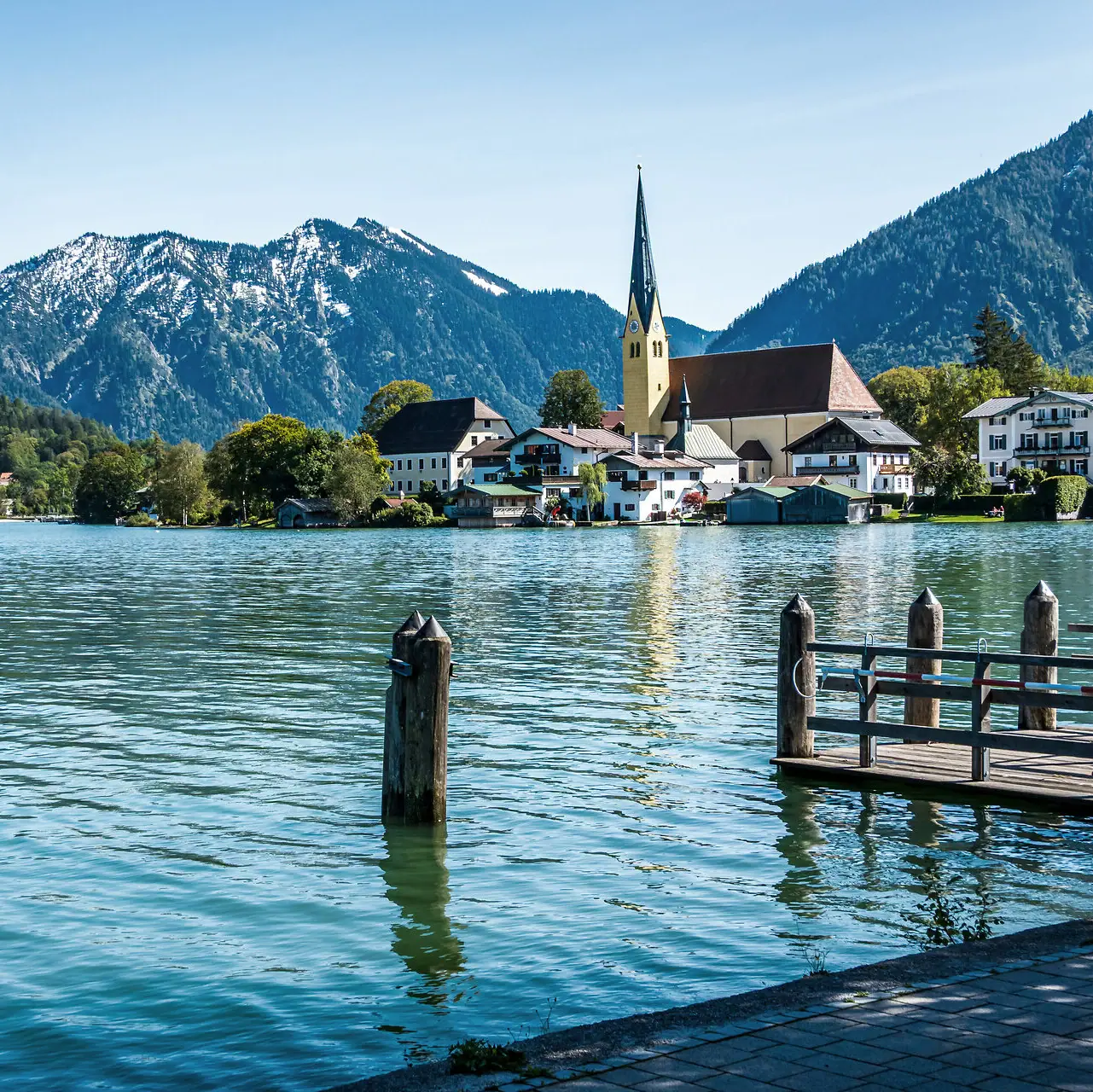 Ein See mit einer Kirche und Bergen im Hintergrund.