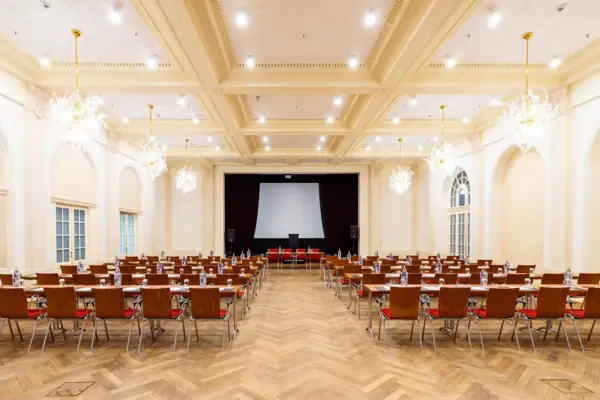 Ein Saal mit vielen Stühlen und einer Projektionsleinwand im A-ROSA Travemünde.