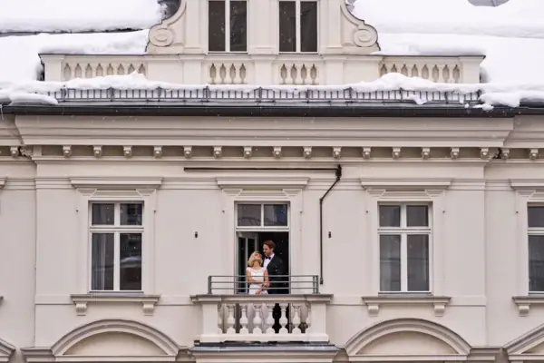 Ein Mann und eine Frau stehen auf einem Balkon vor einem Gebäude.
