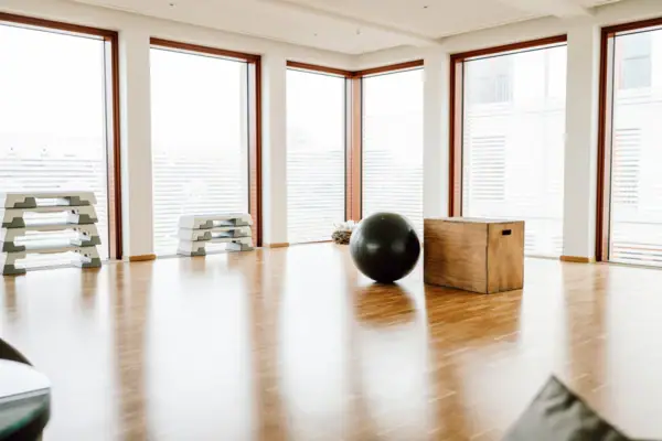 Großer schwarzer Ball auf einem Holzboden in einem Raum mit Fenstern.