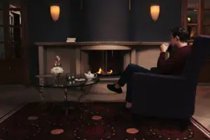 Ein Mann sitzt in einem Sessel und trinkt aus einer Tasse.