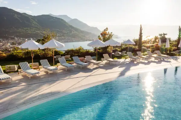 Pool mit Liegestühlen und Sonnenschirmen am Wasser
