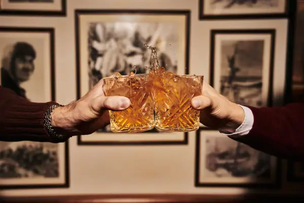 Zwei Hände halten Gläser mit spritzender Flüssigkeit.