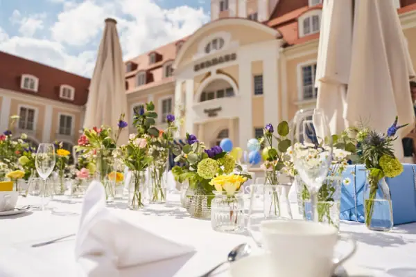 Ein für eine Feier gedeckter Tisch mit Tischgeschirr und Blumengesteck.