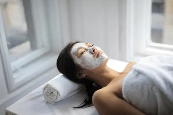 Eine Frau liegt mit einer weißen Maske auf dem Gesicht.