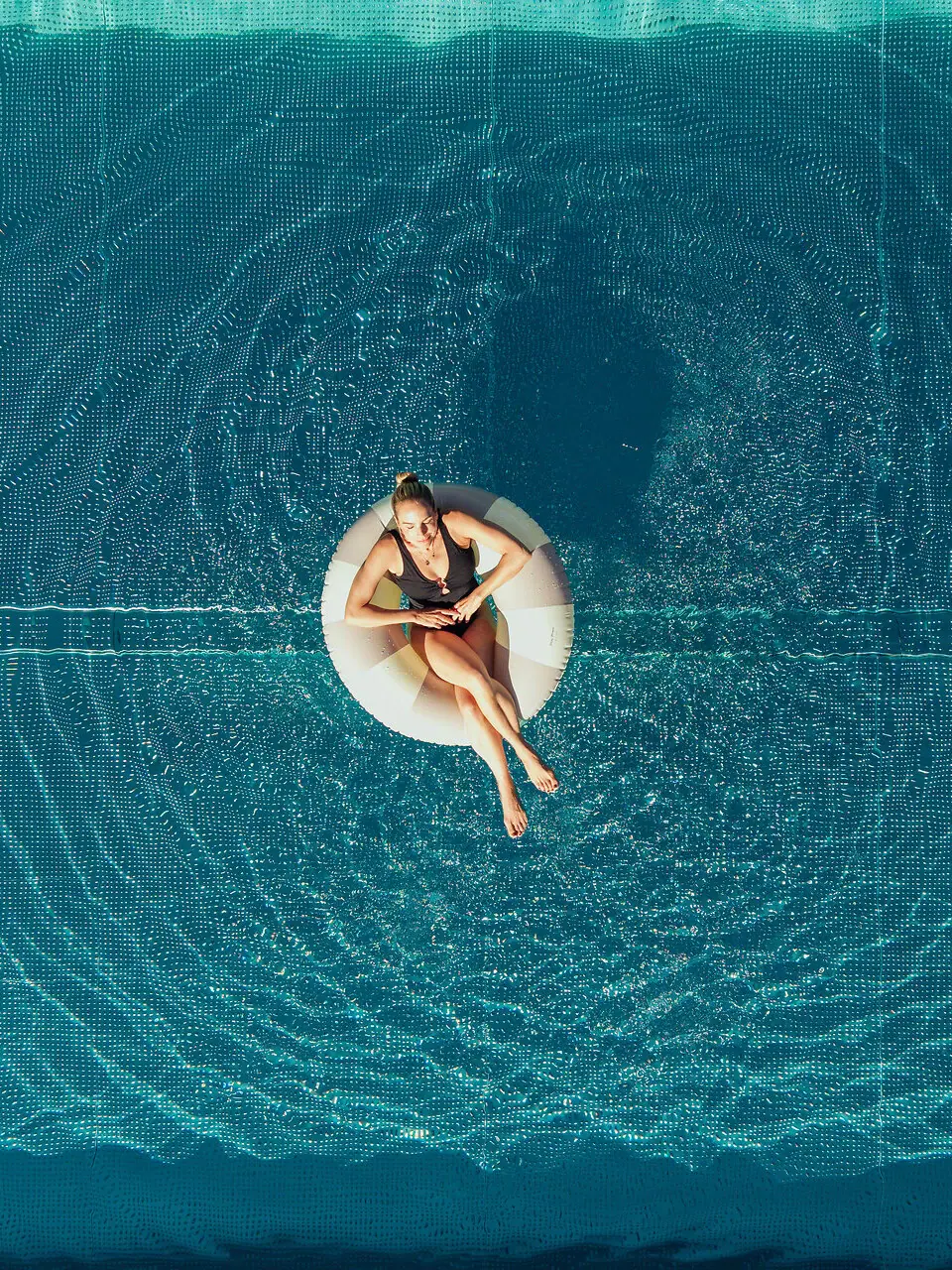 Frau sitzt auf einem Schwimmreifen im Pool