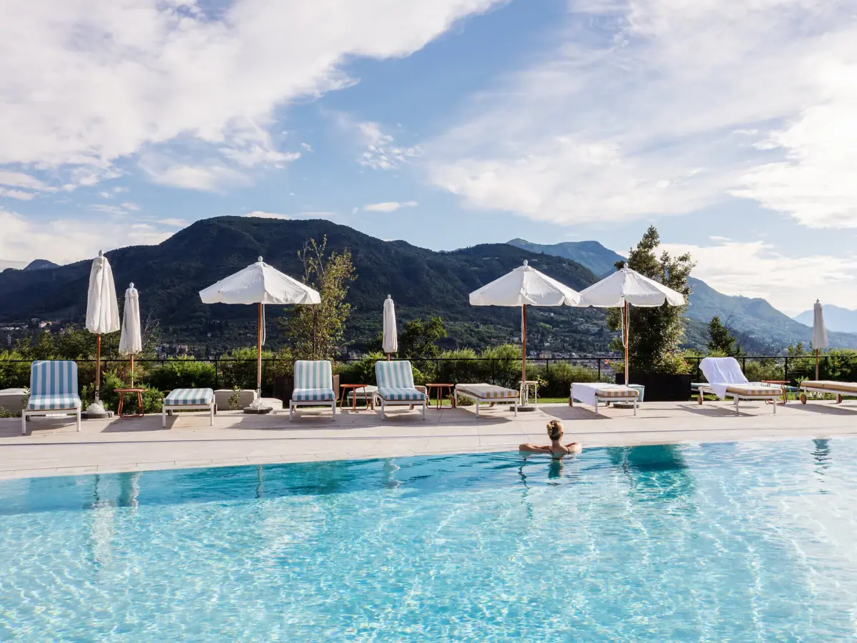 Eine Person im Pool mit Sonnenschirmen und Liegestühlen.