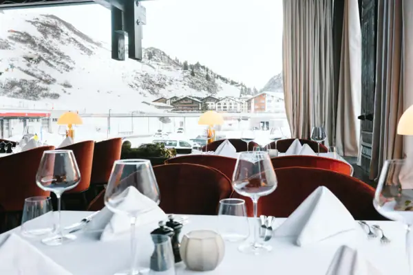 Ein festlich gedeckter Tisch mit Weingläsern vor einer schneebedeckten Bergkulisse.