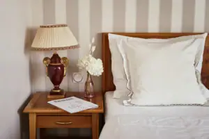 Eine Lampe auf einem Nachttisch neben einem Bett.