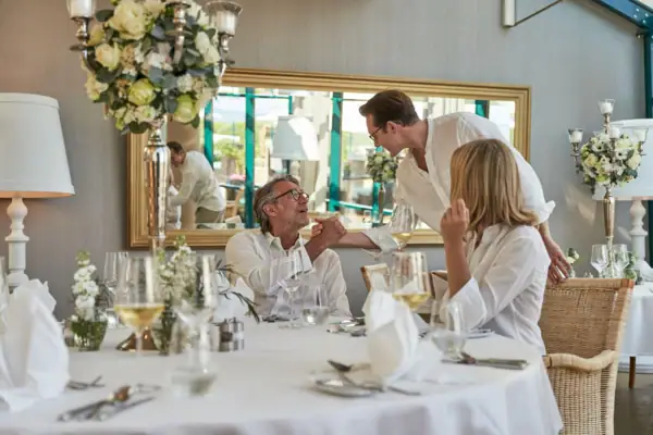 Eine Gruppe von Personen sitzt an einem Tisch mit Blumenarrangement als Tischdekoration.