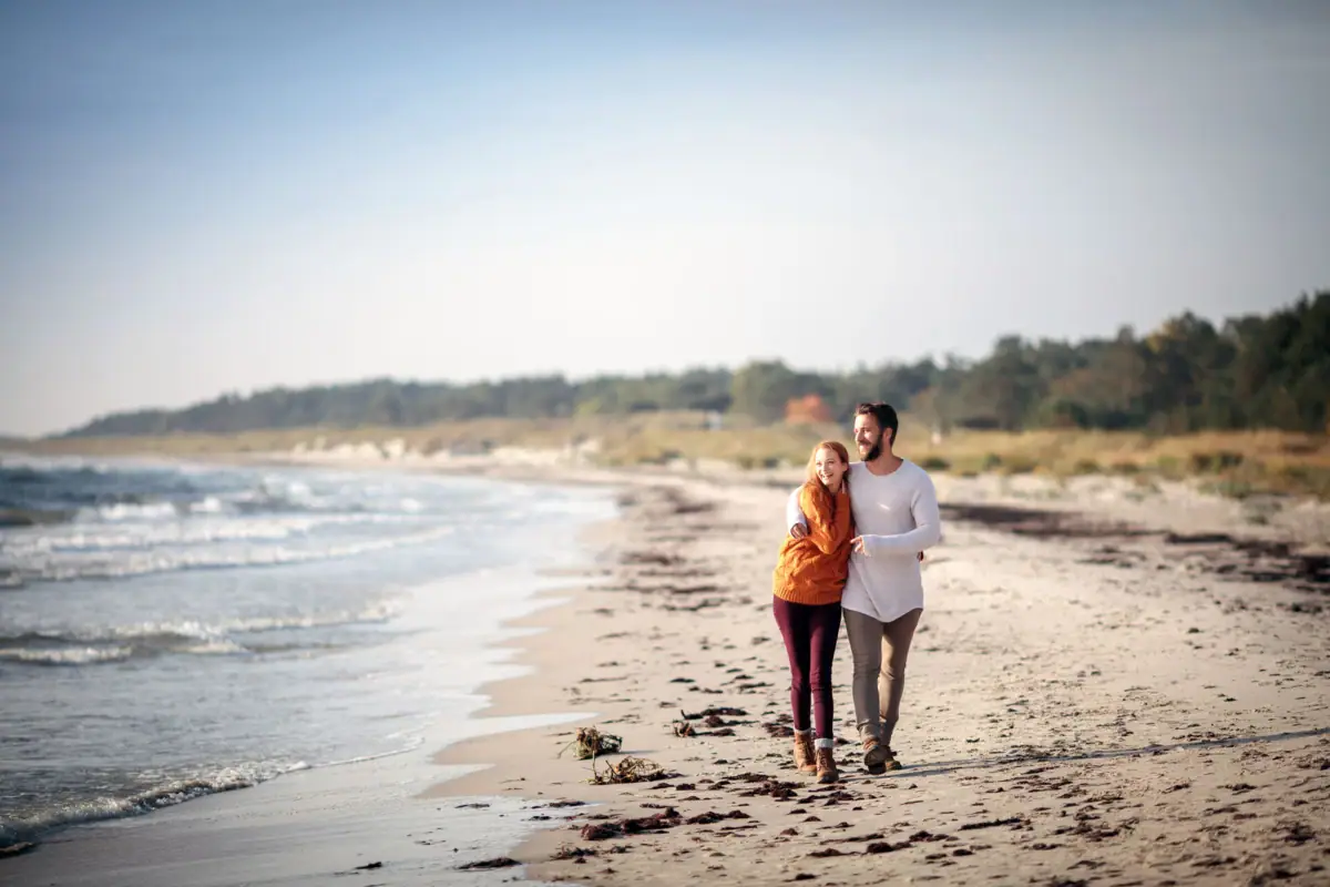 Ein Mann und eine Frau spazieren am Strand entlang.