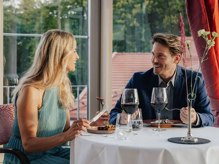 Ein Mann und eine Frau sitzen an einem Tisch mit Weingläsern.