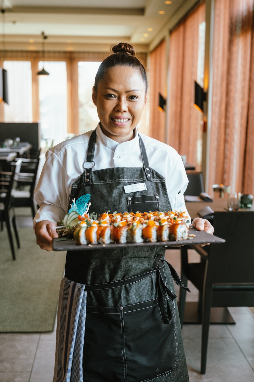 Sushi-Meisterin Noi im Fish Club auf Sylt trägt eine Sushi-Platte in den Händen.