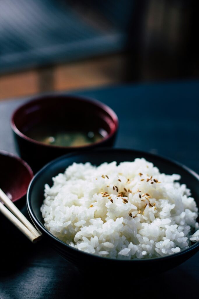 Ein Schälchen mit Sushi-Reis steht auf einem dunklen Tisch.