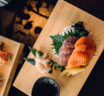 Ein Holzbrett mit Sashimi vom Lachs und Tunfisch.