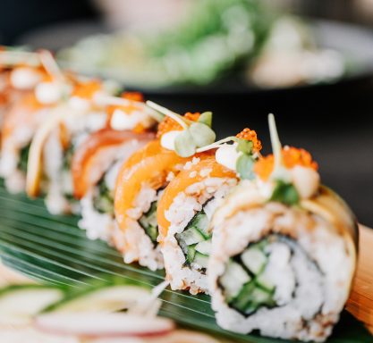Eine Sushi-Rolle wurde auf einem Holzbrett drapiert und mit Fischeiern und Kresse verziert.